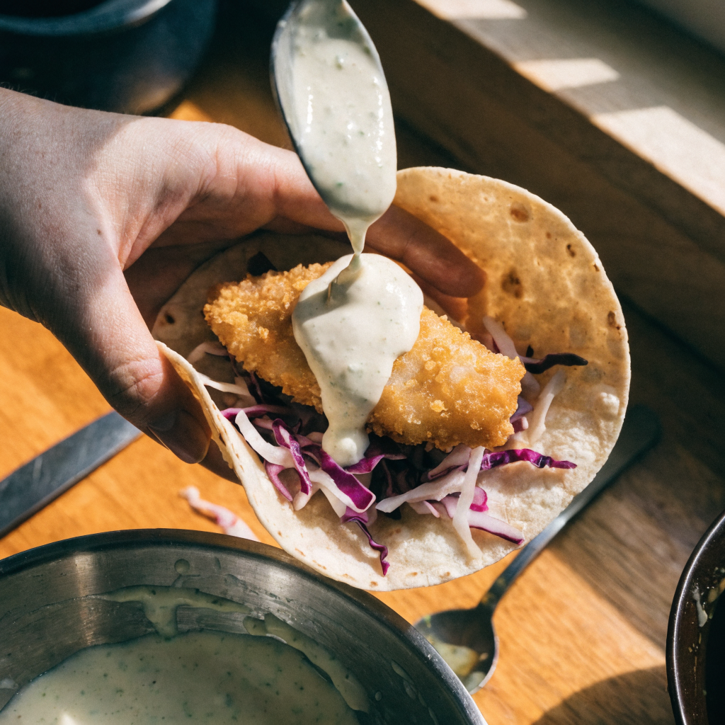 Close-up of crispy cornmeal fish tacos with lime crema